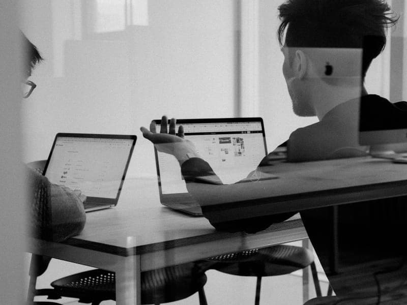 Dos colegas trabajando juntos frente a sus computadoras